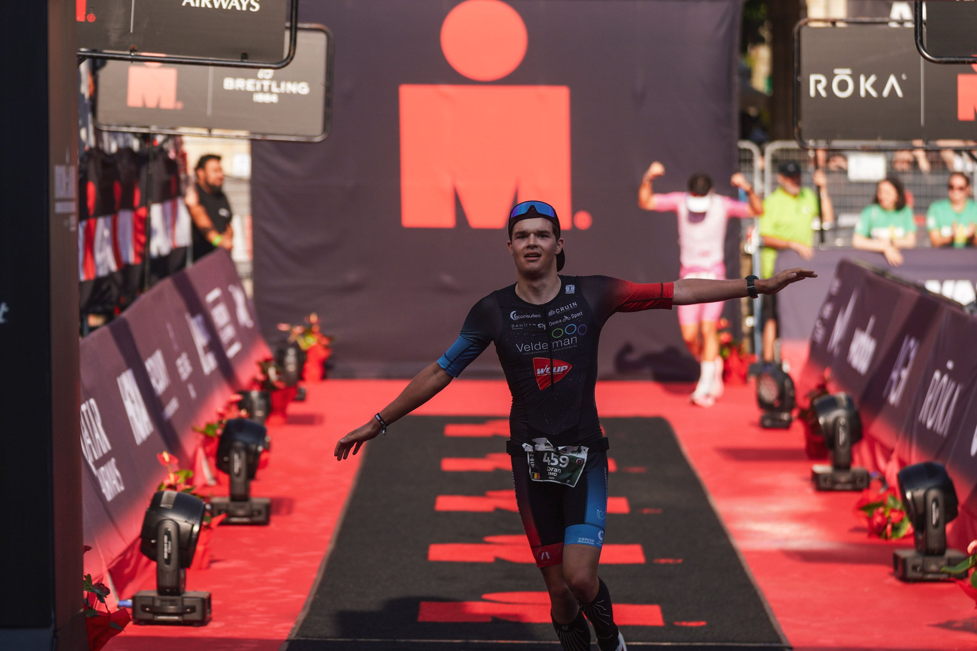 Loran Maes wandelt lachend over de finishmat van IRONMAN 70.3 Knokke-Heist